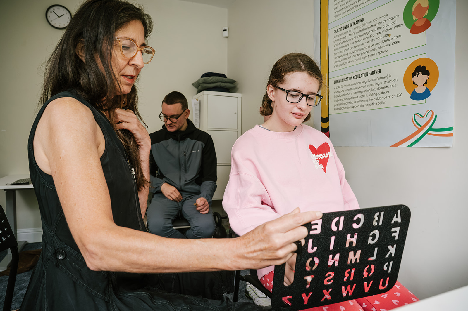Speller communicating on a letterboard with support from a practitioner during a Spelling Alliance of Ireland gathering.