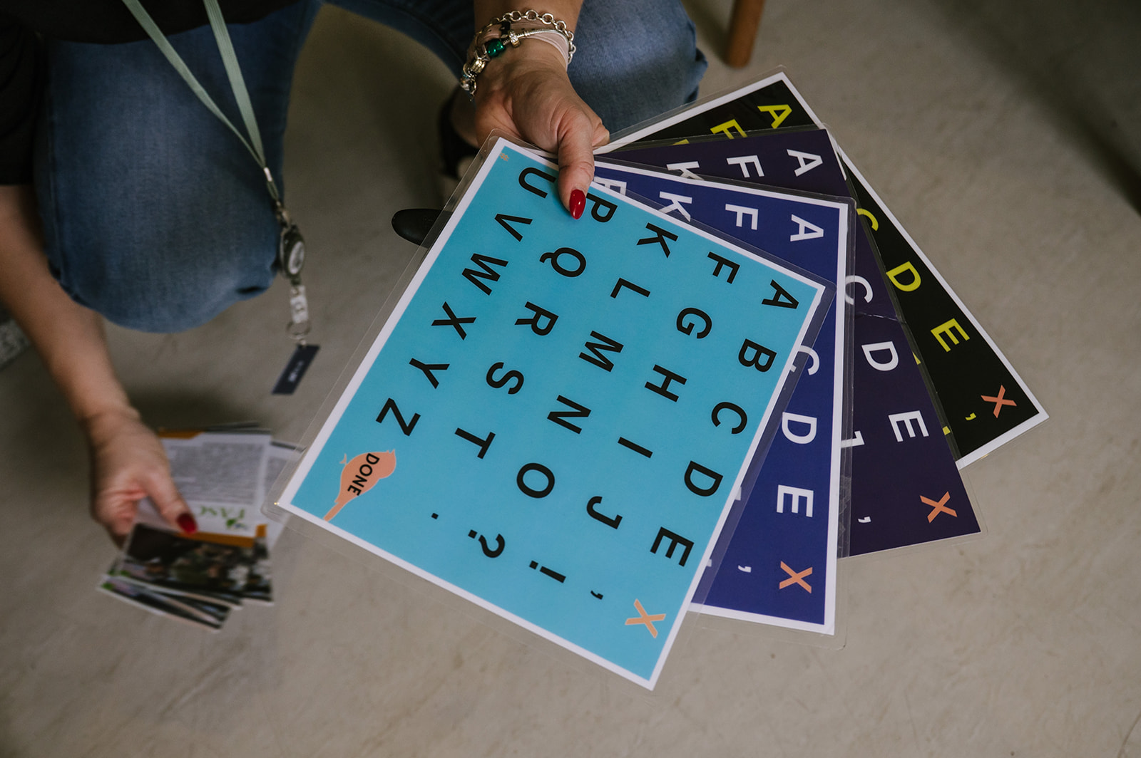 A practitioner holding several colourful letterboards used for spelling communication.